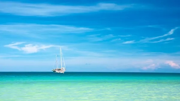 En baad paa havet ses i det meget flotte vand og med en blaa himmel.