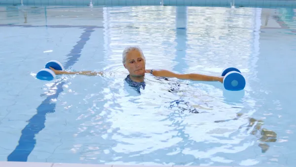 Kvinde træner med haandvaegte i bassin