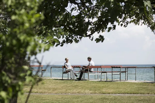 To personer sidder på en bænk ved havet