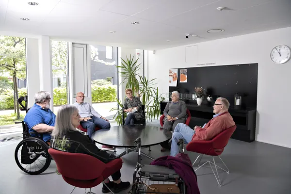 En gruppe af mennesker sidder rundt om bord og snakker