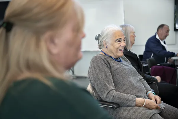 Personer sidder på stole og smiler