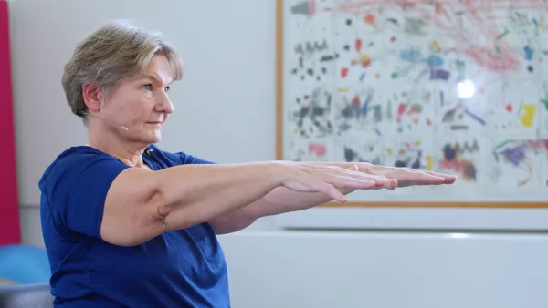 Fysioterapeut sidder med armene oppe